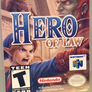 May include: A Nintendo 64 video game cartridge for "Hero of Law." The cover art features a character with blonde hair and a blue tunic, with the title text in blue. The ESRB rating is "Teen."