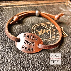May include: A brown leather bracelet with a copper oval charm that says "Faith Over Fear".
