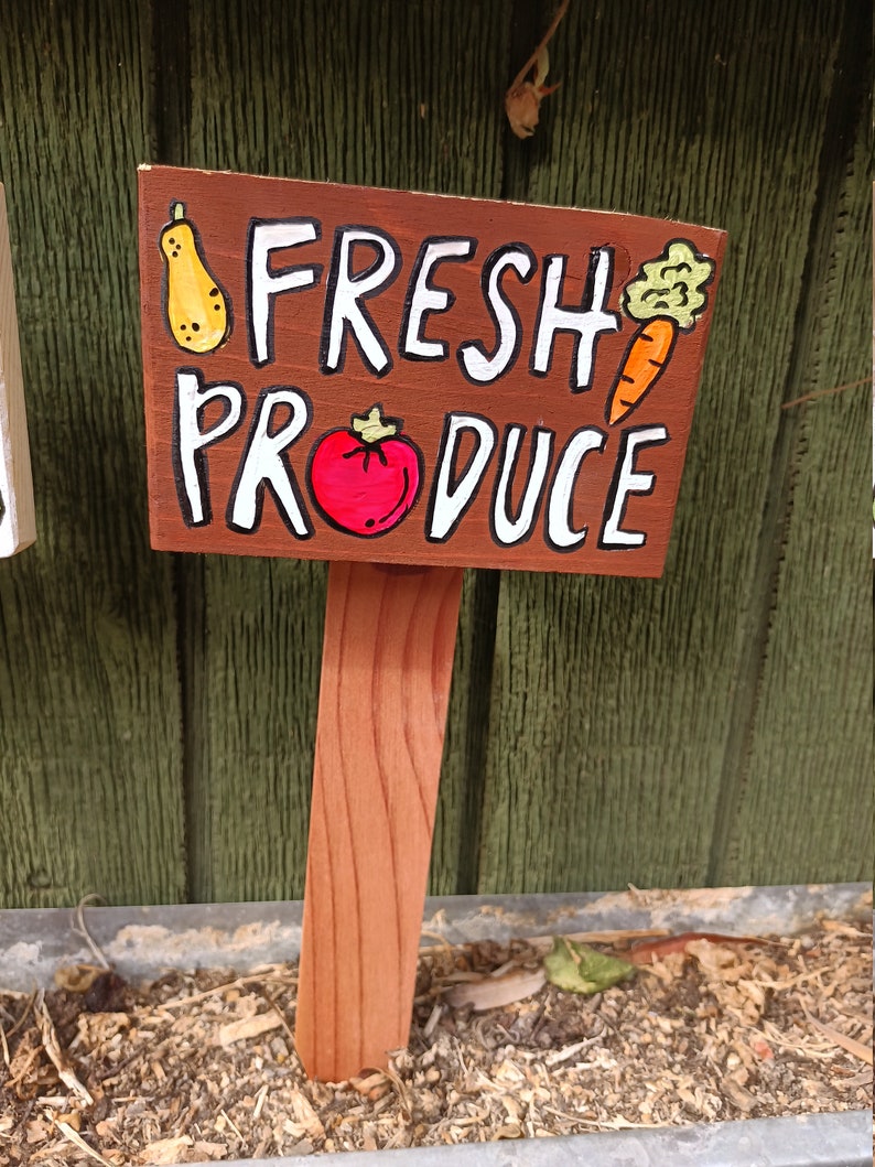 May include: A wooden sign with the words "Fresh Produce" painted in white. The sign is decorated with hand-painted images of a pear, tomato, and carrot.
