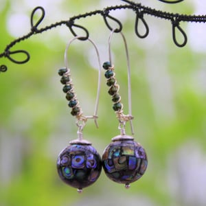 May include: A pair of silver dangle earrings with iridescent abalone shell beads and green glass beads.