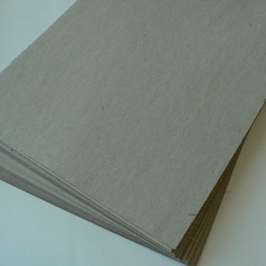 May include: A stack of gray cardboard sheets. The sheets are smooth and have a subtle texture.