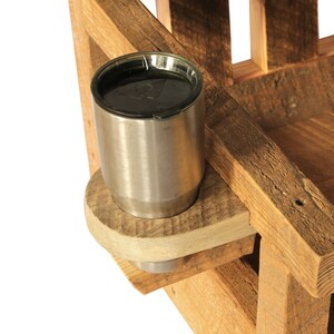 May include: A rustic wooden chair with a built-in cup holder. The cup holder is made of light-colored wood and holds a stainless steel tumbler. The chair is constructed from rough-hewn lumber, showcasing natural wood grain.