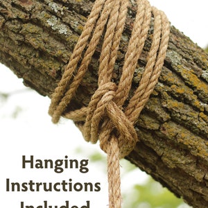 May include: Close-up of a thick, natural-colored rope tied around a tree branch. The rope is knotted and hangs down, with the text "Hanging Instructions Included" at the bottom. The tree bark is brown and textured.