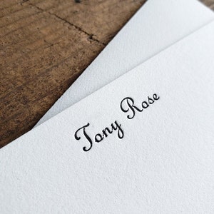 May include: White stationery card with the name "Tony Rose" printed in black cursive script.