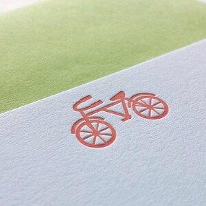 May include: A light blue card with a red bicycle design embossed on the front.