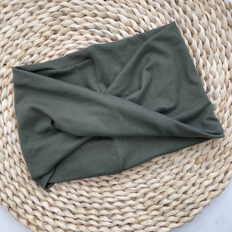 May include: A dark green fabric headband with a twisted knot design. The headband is made of a soft, stretchy material and is perfect for keeping hair out of your face.