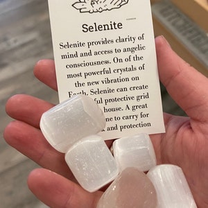 May include: A collection of four white selenite crystals, also known as satin spar, with a card that reads "Selenite provides clarity of mind and access to angelic consciousness. On of the most powerful crystals of the new vibration on Earth. Selenite can create a powerful protective grid in your house. A great stone to carry for peace and protection."