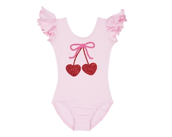 May include: Pink leotard with short ruffled sleeves and a sparkly red cherry design.