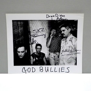 May include: Black and white photograph of a band, with the words "GOD BULLIES" at the bottom. The band members are in a room, and the photo has signatures on it.