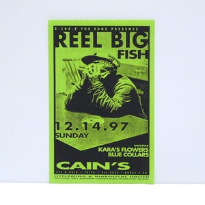 May include: A neon green and black concert poster for Reel Big Fish, featuring a seated figure and the date 12.14.97. The poster also lists Kara's Flowers and Blue Collars, and the venue, Cain's.