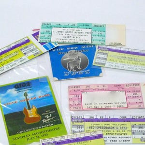 May include: A collection of vintage concert tickets, featuring various bands and artists. The tickets display event details, including dates, venues, and artist names. Some tickets are in plastic sleeves. The color palette includes shades of blue, green, pink, and yellow.