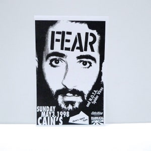 May include: Black and white concert poster featuring a stylized portrait with the word "FEAR" above the eyes. The poster advertises a show at Cain's on May 3, 1998, with Little Wing and Diabolical. Doors open at 7pm.
