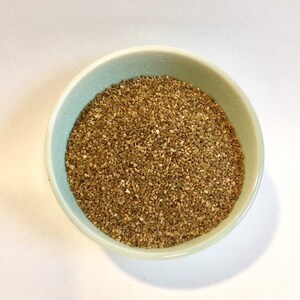 Może przedstawiać: Jasnoniebieska miska wypełniona brązową, surową quinoa.