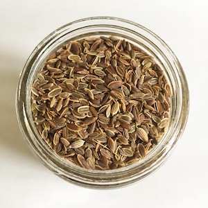 May include: A glass jar filled with brown and tan dill seeds.