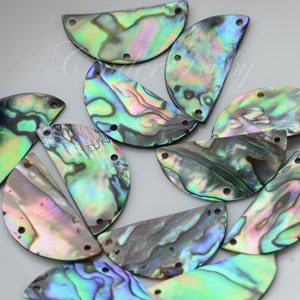 May include: A collection of 12 iridescent abalone shell half-circles with two holes each. The shells are a mix of green, blue, and purple.