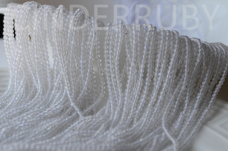 May include: A close-up of a pile of white round beads. The beads are small and have a smooth, polished finish.