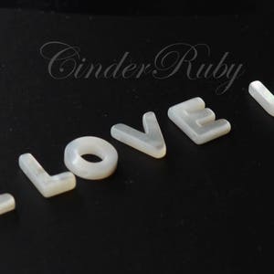 May include: White pearl-like letters spelling out "I LOVE U" on a black background.