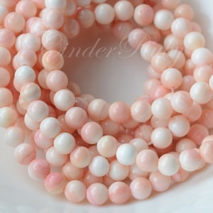 May include: A strand of pink and white shell beads. The beads are round and have a smooth, polished finish.