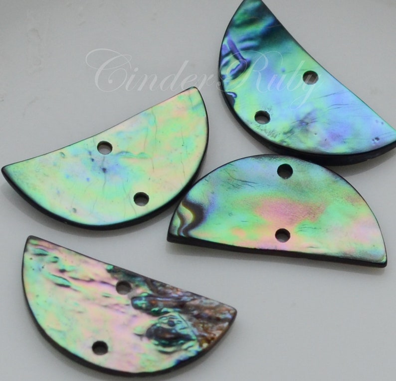 May include: Four iridescent abalone shell half-circle buttons with two holes each. The buttons are a mix of green, blue, and purple.