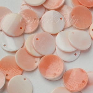 May include: A collection of round, flat beads in shades of peach and white. Each bead has a small hole for stringing. The beads have a glossy finish and a subtle, textured surface. Ideal for jewelry making and crafts.