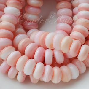 May include: A strand of pink and white shell beads. The beads are round and have a smooth, polished finish.