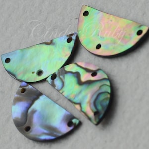 May include: Four iridescent abalone shell half-circles with two holes each. The shells are a mix of green, blue, and purple.