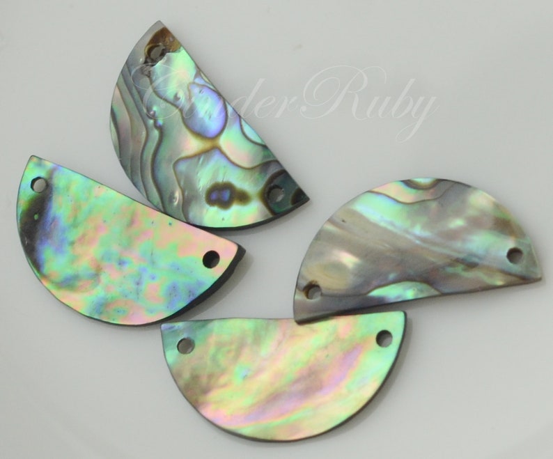 May include: Four iridescent abalone shell half-circle shapes with two holes each. The shells have a green, blue, and purple iridescent sheen.
