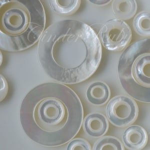 May include: A collection of white mother of pearl shell rings with varying sizes and widths. The rings have a smooth, iridescent finish and are perfect for jewelry making.