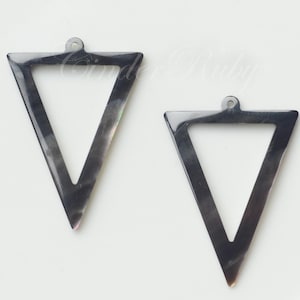 May include: Two black triangle-shaped pendants with a hole at the top for hanging. The pendants are made of a material that has a pearlescent sheen.