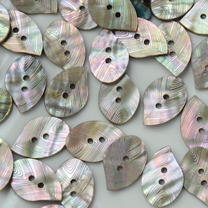 May include: A collection of leaf-shaped buttons crafted from iridescent mother-of-pearl. Each button features a two-hole design and a distinct, natural wavy grain pattern that reflects light with shifting hues of pink, green, and silver.