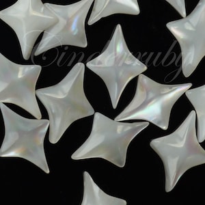 May include: A collection of white, four-pointed star-shaped beads with an iridescent, pearlescent finish. Each bead features a smooth, curved surface that reflects light, creating subtle rainbow highlights against the stark black background.