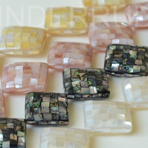 May include: A strand of rectangular, iridescent mosaic tile beads in shades of white, pink, yellow, and black. The beads are made of mother of pearl.