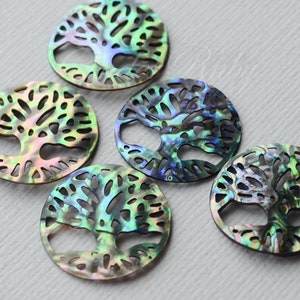May include: Five round, iridescent abalone shell pendants with a tree of life design cut out. The pendants are approximately 2 inches in diameter and have a green, blue, and purple color scheme.