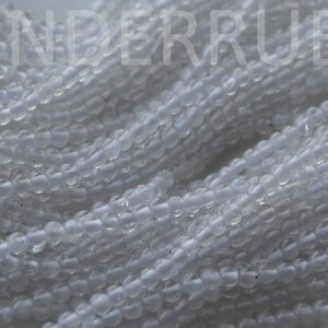 May include: A strand of small, round, translucent white beads. The beads have a slightly iridescent sheen.