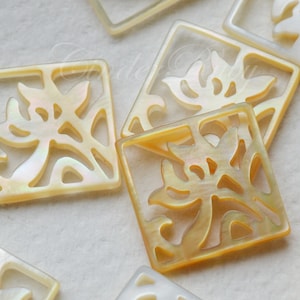 May include: A set of six square-shaped, iridescent, mother-of-pearl tiles with a floral design cut out. The tiles are a pale yellow color with a subtle shimmer.