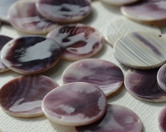 May include: A collection of circular, flat shell beads featuring a polished, glossy finish with swirling patterns of deep purple, lavender, and creamy white. Each bead has a small, singular hole near the edge for threading, showcasing natural variations.
