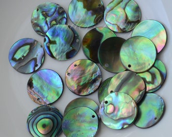May include: A collection of 17 iridescent abalone shell round discs with a hole in the center. The discs are various shades of green, blue, and purple.