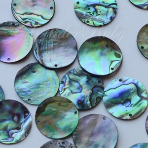 May include: A collection of iridescent round abalone shell sequins with two holes each. The sequins are various shades of green, blue, and purple.