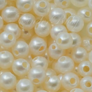 May include: A close-up image of a pile of white pearl beads with holes for stringing. The beads are smooth and shiny, and they are perfect for making jewelry.