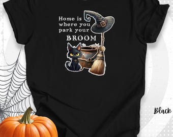 Könnte beinhalten: Schwarzes T-Shirt mit einem Halloween-Motiv. Das Design zeigt einen Hexenhut, einen Kessel, einen Besen und eine schwarze Katze mit dem Text "Home is where you park your BROOM". Ein oranger Kürbis und ein Spinnennetz sind im Hintergrund.