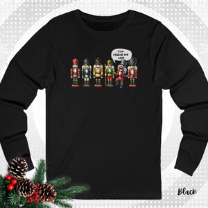 May include: Black long-sleeve shirt featuring a graphic of six colorful nutcracker figures. One nutcracker has a speech bubble that says "You crack me up!!" The word "Black" is printed at the bottom right.