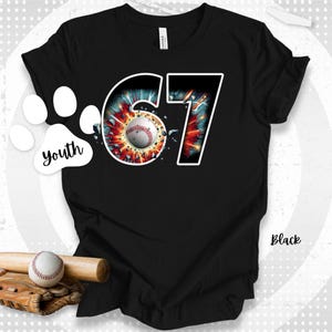 May include: Black youth t-shirt with a baseball-themed graphic. The design features the number 67 with a baseball in the center, surrounded by a burst of color. A baseball bat, ball, and glove are at the bottom. The word "Youth" is in a paw print.