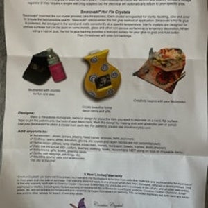 May include: A set of instructions for using "Stained Glass" and "Swarovski" crystals to decorate a ceramic vase. The instructions include a list of recommended crystals, a description of the process, and a disclaimer about the warranty. The image also shows a black and pink spray bottle, a yellow ceramic vase with a floral design, and a plate of food.
