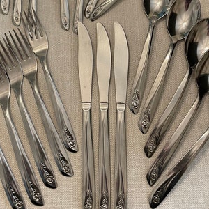 May include: A set of silverware with a floral design on the handles. The set includes forks, knives, spoons, and serving utensils.