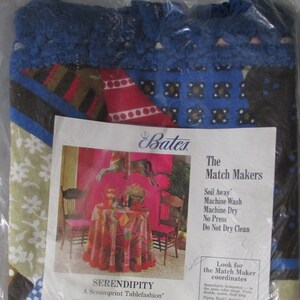 May include: A packaging display for a Bates Serendipity tablecloth in a blue, red, and white geometric pattern. The packaging includes a smaller image of a table setting with a red tablecloth and two chairs. The text on the packaging reads "The Match Makers", "Soil Away", "Machine Wash", "Machine Dry", "No Press", "Do Not Dry Clean", "Look for the Match Maker coordinates", "Serendipity designed - in the same style - are: Twin, double, queen, king, and round tablecloths, placemats, napkins, draperies and cafe curtains.  Choose these coordinates to mix or match with Serendipity tablecloths."