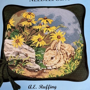 May include: Needlepoint kit for a decorative pillow featuring a rabbit and yellow flowers. The finished size is 12" x 12". The design is printed in full color on 14 mesh interlock 100% cotton canvas. The kit includes cotton floss, chart, needle, and instructions.