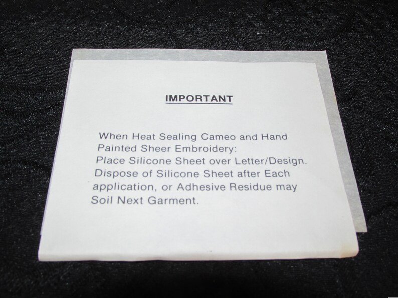 May include: A white sheet of paper with the word "IMPORTANT" printed in black at the top. The text below explains how to use a silicone sheet when heat sealing cameo and hand painted sheer embroidery.