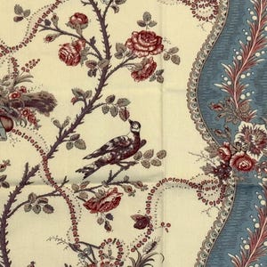 May include: A cream-colored fabric featuring a repeating pattern of dark red roses, thorny branches, and a bird perched on a stem. A wide, vertical blue wavy band with a lace-like border and floral motifs runs along the right side of the textile.