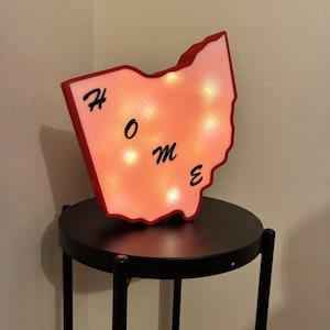 May include: A red and white light-up sign shaped like the state of Ohio with the word "HOME" spelled out in black lettering.