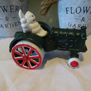Vintage cast iron counter top advertising Michelin man driving a tractor vintage toy in great condition
